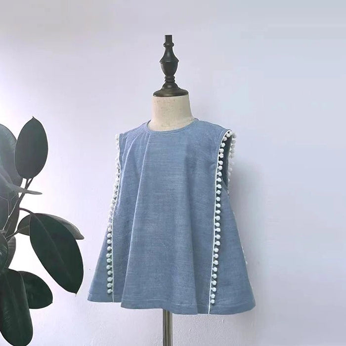 A blue sleeveless blouse made with the Longan Craft Sleeveless Blouse Free Sewing Pattern for beginners is displayed on a dress form beside a green leafy plant, set against a plain light background.