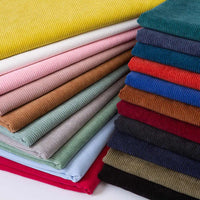 Stacks of Longan Craft Thick 8 Wale Corduroy Fabric By the Yard—soft upholstery fabric in yellow, pink, red, blue, gray, green, brown, navy, and black—arranged neatly. Great for dressmaking or vibrant polyester fabric accents.