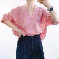 A person wearing a pink Women's V-neck Oversize Shirt made from the Longan Craft PDF Sewing Pattern, paired with dark high-waisted pants and a smartwatch, takes a mirror selfie.