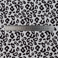A 20cm metal ruler rests on a white surface displaying Longon Craft’s Animal Patterned Minky Fabric by the Yard, featuring a striking black leopard dot and cow print, ideal for plushies and crafts.