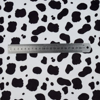 A 20cm metal ruler is placed on a white surface featuring Longon Craft's Animal Patterned Minky Fabric by the yard, with leopard dot cow spots, perfect for plushies and baby blankets.