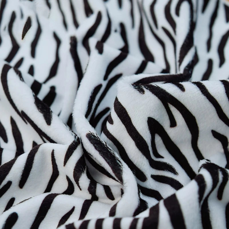 A close-up of Longon Craft Animal Patterned Minky Fabric by the Yard, featuring plush polyester with leopard dot or cow print patterns, soft texture, and slight folds—ideal for plushies and crafts.