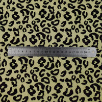 A metal ruler showing 0–20 cm lies horizontally on Longon Craft’s Animal Patterned Minky Fabric by the yard, featuring a black and tan leopard dot print—plush floral cuddle minky material ideal for plushies.