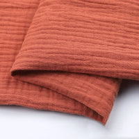 Longan craft’s Solid Color Cotton Double Gauze Fabric By The Yard features rust-colored, textured bubble gauze muslin—perfect for quilting or baby clothing projects.