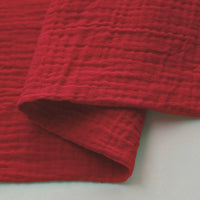 A close-up of Solid Color Cotton Double Gauze Fabric by Longan craft, featuring a red crinkled texture—perfect for quilting or soft baby clothing. Also known as Bubble Gauze Muslin, it's sold by the yard and ideal for babies.