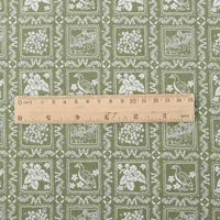 A wooden ruler rests on Longon Craft’s Floral Flannel Fabric by the yard, showcasing its green cotton print with white birds, flowers, and framed scenes—ideal for dresses, clothes, sewing, and crafts.