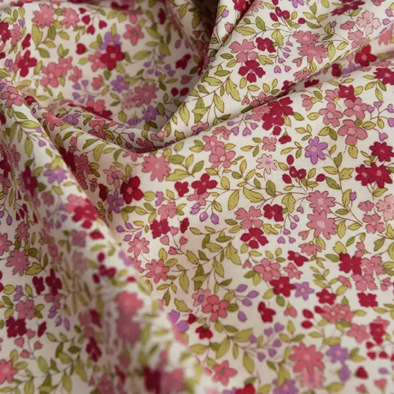 A close-up of Longan craft’s Floral Printed Poplin Fabric by the Yard, featuring small pink, red, and purple flowers with green leaves on light cotton—lightweight poplin material, perfect for quilting or dressmaking projects.