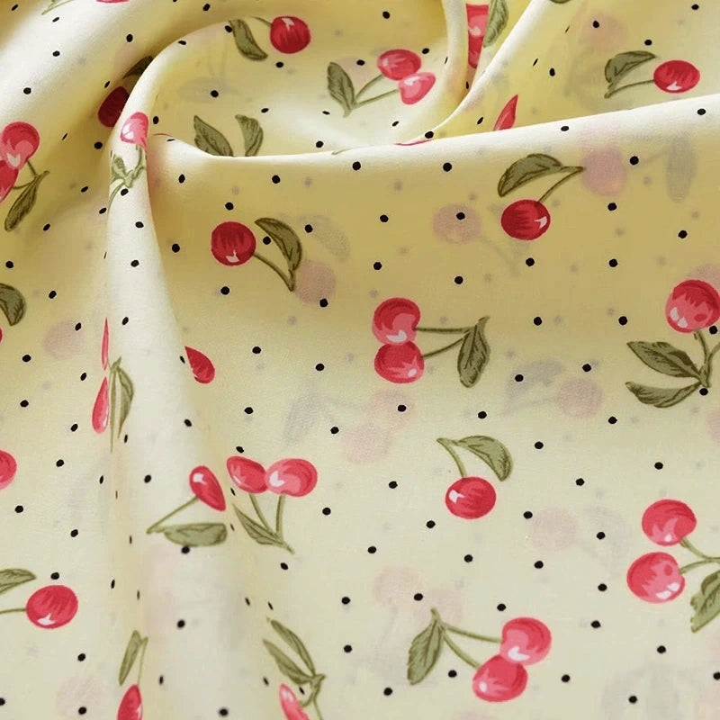Fabric with cherry and polka dot pattern on a yellow background