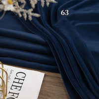 A folded piece of Longon Craft Stretch Minky Fabric by the yard in dark blue lies on a wooden surface, beside a magazine and dried flowers. The number 63 is printed on this four-way stretch cuddle minky material for DIY projects.