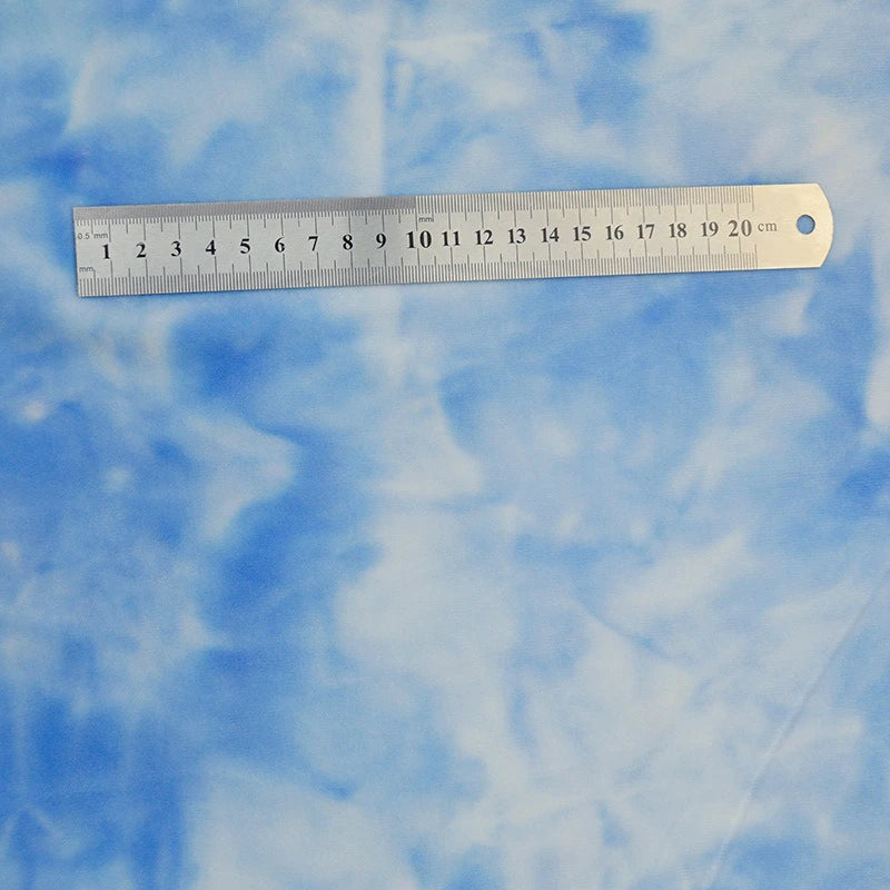 A 20-centimeter metal ruler is placed diagonally on Longon Craft's Stretch Rainbow Minky Fabric by the yard, a gradient colorful printed floral material ideal for DIY plushies, toys, and clothing.