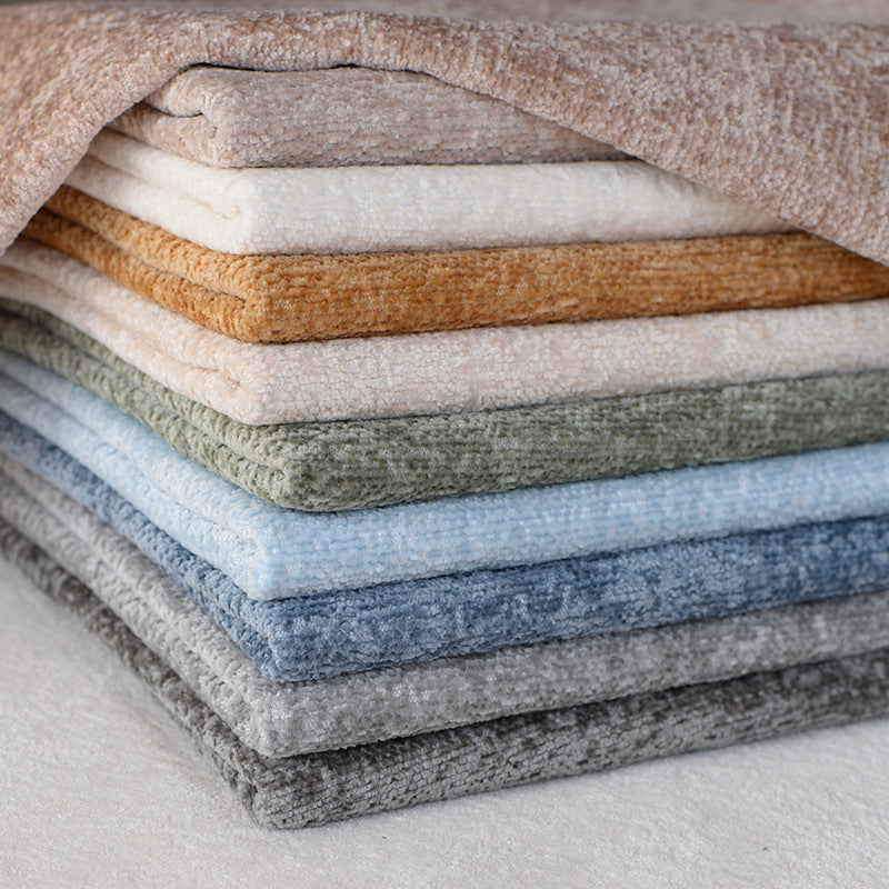 A neatly stacked pile of folded towels in various neutral and pastel colors is shown, with one towel draped over the top.