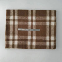 A piece of Multicolor Plaid Mammoth Flannel Fabric by Longan Craft rests on a flat surface with a metal ruler for scale, showcasing the soft brushed polyester cotton flannelette ideal for shirts.