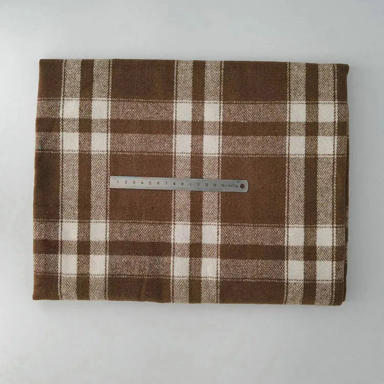 A piece of Multicolor Plaid Mammoth Flannel Fabric by Longan Craft rests on a flat surface with a metal ruler for scale, showcasing the soft brushed polyester cotton flannelette ideal for shirts.