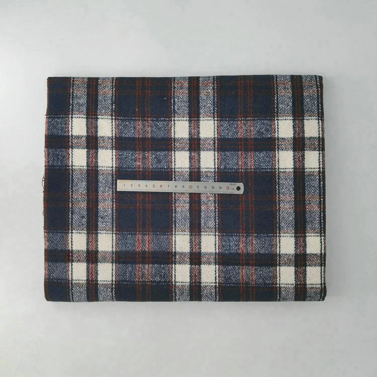 A folded piece of Multicolor Plaid Mammoth Flannel Fabric by Longan Craft is shown with a metal ruler for scale, set on a light gray background. This brushed polyester cotton flannelette is ideal for comfy shirts.