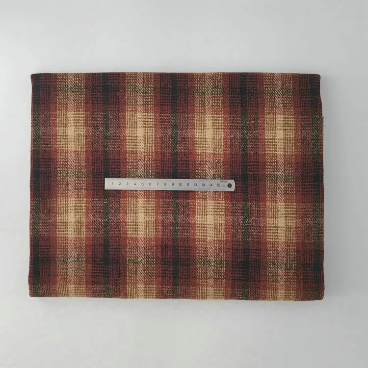 A piece of Multicolor Plaid Mammoth Flannel Fabric by Longan Craft is laid flat on a white surface with a metal ruler on top, highlighting the scale. This soft brushed polyester-cotton textile is ideal for comfy shirts and available by the yard.