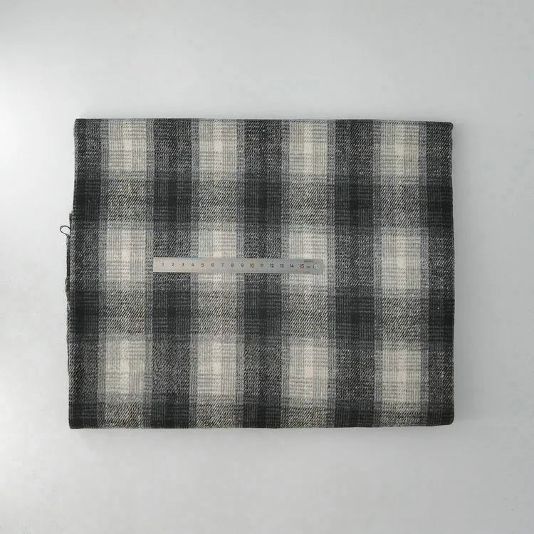 A piece of Longan Craft Multicolor Plaid Mammoth Flannel Fabric by the yard is shown in black, gray, and white with a ruler placed across for scale—brushed polyester cotton flannelette ideal for comfy shirts.