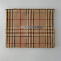 A piece of Longan Craft Multicolor Plaid Mammoth Flannel Fabric by the yard, featuring a tan, black, and red plaid pattern, is displayed folded on a white surface with a metal ruler in centimeters for scale.