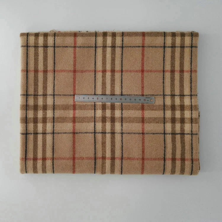 A piece of Longan Craft Multicolor Plaid Mammoth Flannel Fabric by the yard, featuring a tan, black, and red plaid pattern, is displayed folded on a white surface with a metal ruler in centimeters for scale.