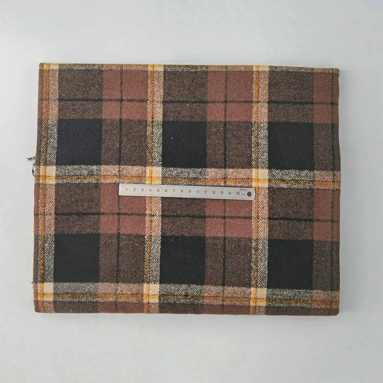 A piece of Longan Craft Multicolor Plaid Mammoth Flannel Fabric by the yard is folded on a white surface, with a ruler across it to show its width. This brushed polyester cotton flannel is ideal for comfy shirts.
