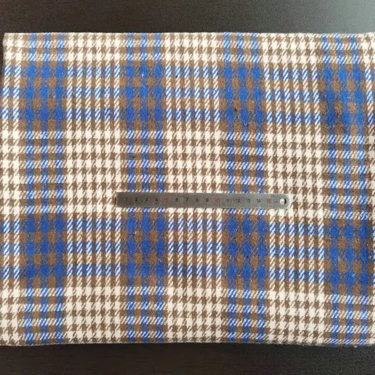 The Longan Craft Multicolor Plaid Mammoth Flannel Fabric By The Yard, a soft brushed polyester cotton textile for shirts, is displayed flat with a blue, brown, and white design. A silver 20cm ruler lies across the material.