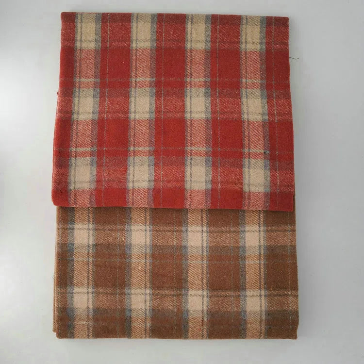 Two folded blankets made from Longan Craft's Multicolor Plaid Mammoth Flannel Fabric, a cozy brushed polyester cotton material, are stacked on a white surface. The top is red plaid with beige/gray lines; the bottom is brown plaid.