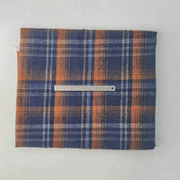 A piece of Longan Craft Multicolor Plaid Mammoth Flannel Fabric by the yard in blue, orange, and white rests on a white surface with a ruler across it for scale; brushed polyester cotton flannelette, perfect for shirts.