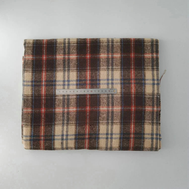 A piece of Longan Craft Multicolor Plaid Mammoth Flannel Fabric by the yard, a comfy brushed polyester cotton textile for shirts, is folded on a gray surface with a ruler on top for scale.