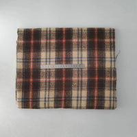 A piece of Longan Craft Multicolor Plaid Mammoth Flannel Fabric by the yard, a comfy brushed polyester cotton textile for shirts, is folded on a gray surface with a ruler on top for scale.
