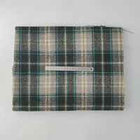 A folded piece of Longan Craft Multicolor Plaid Mammoth Flannel Fabric by the yard is laid flat on a white surface, showing green, black, beige, and teal plaid with a 15 cm metal ruler on top for scale.