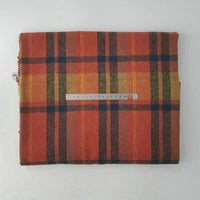 A folded piece of Longan Craft Multicolor Plaid Mammoth Flannel Fabric by the yard with a clear ruler in centimeters on top rests on a plain white surface. This soft, brushed polyester-cotton textile is ideal for shirts.