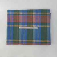 A piece of Longan Craft Multicolor Plaid Mammoth Flannel Fabric is displayed on a white surface with a ruler on top for scale. This brushed polyester cotton textile is ideal for comfy shirts and sold by the yard.