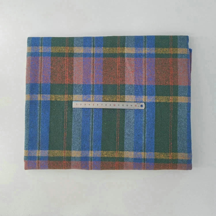 A piece of Longan Craft Multicolor Plaid Mammoth Flannel Fabric is displayed on a white surface with a ruler on top for scale. This brushed polyester cotton textile is ideal for comfy shirts and sold by the yard.