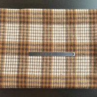 A metal ruler rests on Longan Craft’s Multicolor Plaid Mammoth Flannel Fabric, showcasing the brown and cream checkered polyester cotton blend—ideal for comfy shirts.
