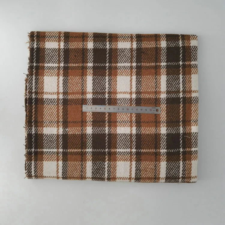 A folded piece of Longan Craft Multicolor Plaid Mammoth Flannel Fabric by the yard, a comfy brushed polyester cotton textile for shirts, is displayed on a white surface with a silver ruler on top for scale.