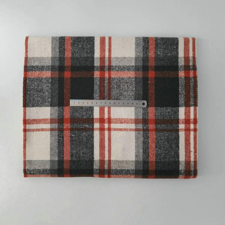 A piece of Longan Craft Multicolor Plaid Mammoth Flannel Fabric by the yard in black, white, and red lies on a flat surface, with a metal ruler across it for scale. This brushed polyester cotton material is ideal for shirts and crafts.
