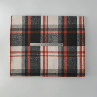 A piece of Longan Craft Multicolor Plaid Mammoth Flannel Fabric by the yard in black, white, and red lies on a flat surface, with a metal ruler across it for scale. This brushed polyester cotton material is ideal for shirts and crafts.