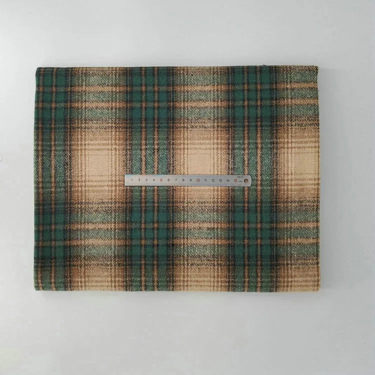 A folded piece of Multicolor Plaid Mammoth Flannel Fabric by Longan Craft is displayed on a white surface with a metal ruler on top for scale, showing its soft brushed polyester cotton texture—ideal for shirts and crafts.