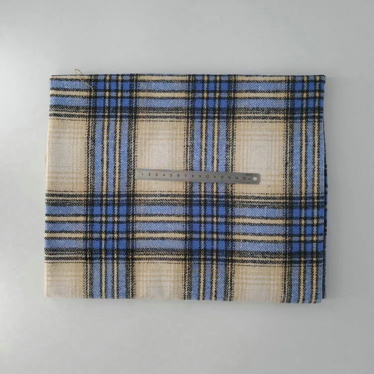A piece of Longan Craft Multicolor Plaid Mammoth Flannel Fabric by the yard lies flat on a white surface with a metal ruler on top for scale. The comfy brushed polyester-cotton flannelette is ideal for shirts.