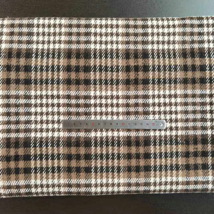 A piece of Multicolor Plaid Mammoth Flannel Fabric by Longan Craft lies flat with a silver measuring tape across it, showcasing the soft brushed polyester cotton textile perfect for shirts.