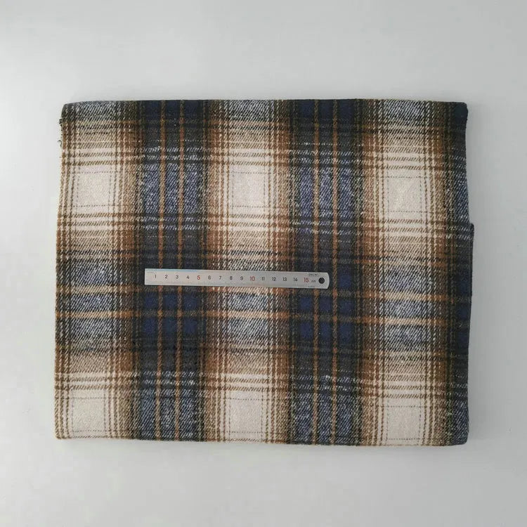 A piece of Multicolor Plaid Mammoth Flannel Fabric by Longan Craft, made from brushed polyester-cotton for shirts, lies folded on a white surface with a clear ruler on top to show its size.