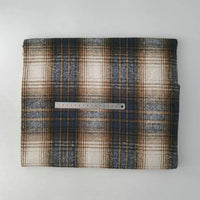 A piece of Multicolor Plaid Mammoth Flannel Fabric by Longan Craft, made from brushed polyester-cotton for shirts, lies folded on a white surface with a clear ruler on top to show its size.
