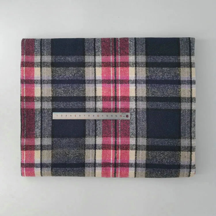 A folded Longan Craft Multicolor Plaid Mammoth Flannel Fabric by the yard, in navy, red, grey, and cream tones, lies on a white surface with a metal ruler across the middle for scale.