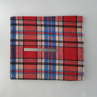 A folded Longan Craft Multicolor Plaid Mammoth Flannel Fabric (by the yard) in red, blue, and white rests on a white surface, with a 30cm metal ruler across it to show scale. Ideal comfy flannelette for shirts.