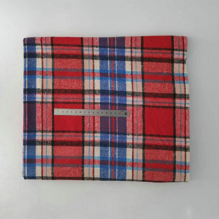 A folded Longan Craft Multicolor Plaid Mammoth Flannel Fabric (by the yard) in red, blue, and white rests on a white surface, with a 30cm metal ruler across it to show scale. Ideal comfy flannelette for shirts.