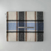 A folded Multicolor Plaid Mammoth Flannel Fabric by Longan Craft lies on a light surface with a metal ruler showing its size. The comfy brushed polyester cotton flannelette features black, brown, blue, and cream tones—great for shirts.