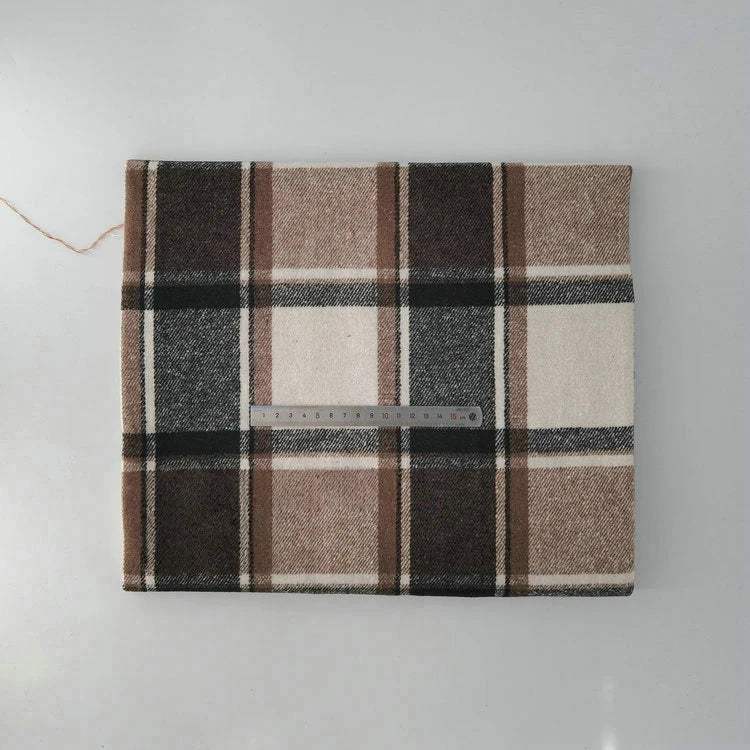 A folded Longan Craft Multicolor Plaid Mammoth Flannel Fabric by the yard, a brushed polyester-cotton blend for shirts, is shown with a metal ruler for scale against a light gray background.