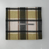 A piece of Multicolor Plaid Mammoth Flannel Fabric by Longan Craft, featuring green, yellow, white, and black tones, is displayed folded on a white surface with a metal ruler across its center for scale.