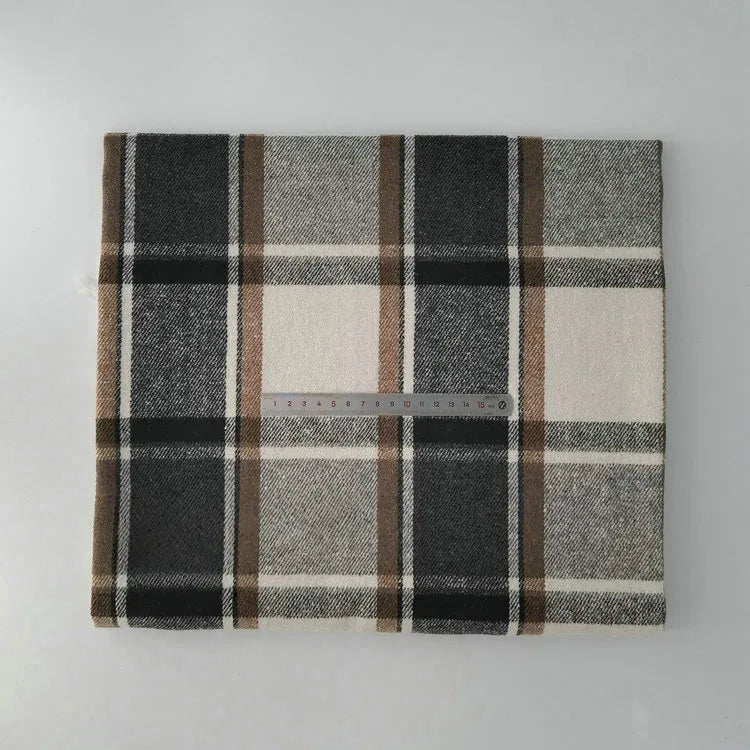 A folded piece of Longan Craft Multicolor Plaid Mammoth Flannel Fabric by the yard, made of brushed polyester cotton, is shown in black, brown, beige, and white tones with a clear plastic ruler on top for scale.