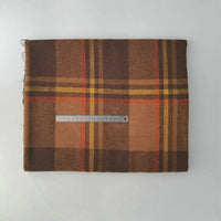 A folded Multicolor Plaid Mammoth Flannel Fabric by Longan Craft lies on a white surface with a metal ruler across the center, displaying its width. This brushed polyester cotton flannel is ideal for comfy shirts and sold by the yard.