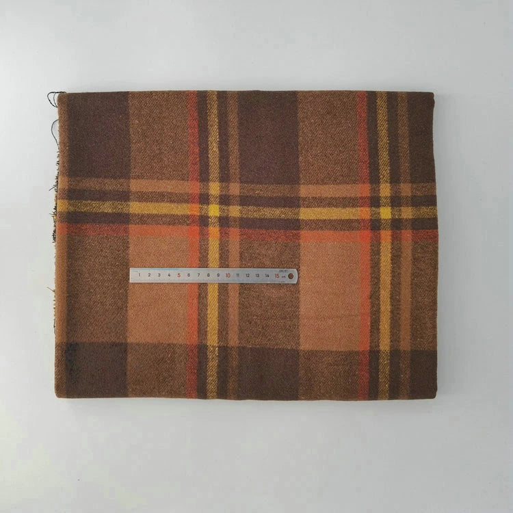 A folded Multicolor Plaid Mammoth Flannel Fabric by Longan Craft lies on a white surface with a metal ruler across the center, displaying its width. This brushed polyester cotton flannel is ideal for comfy shirts and sold by the yard.